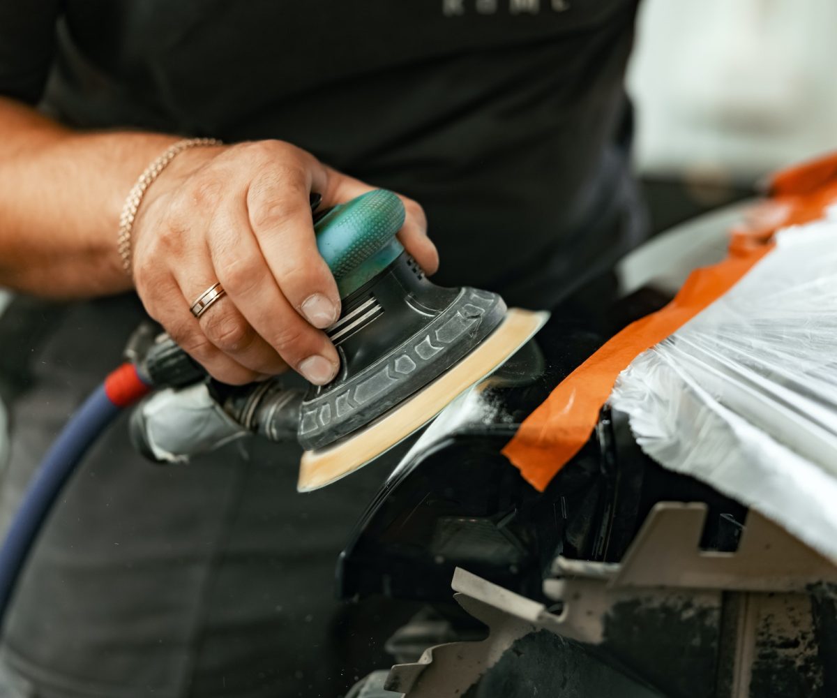 Close up of car cleaner polishing headlight with polish machine