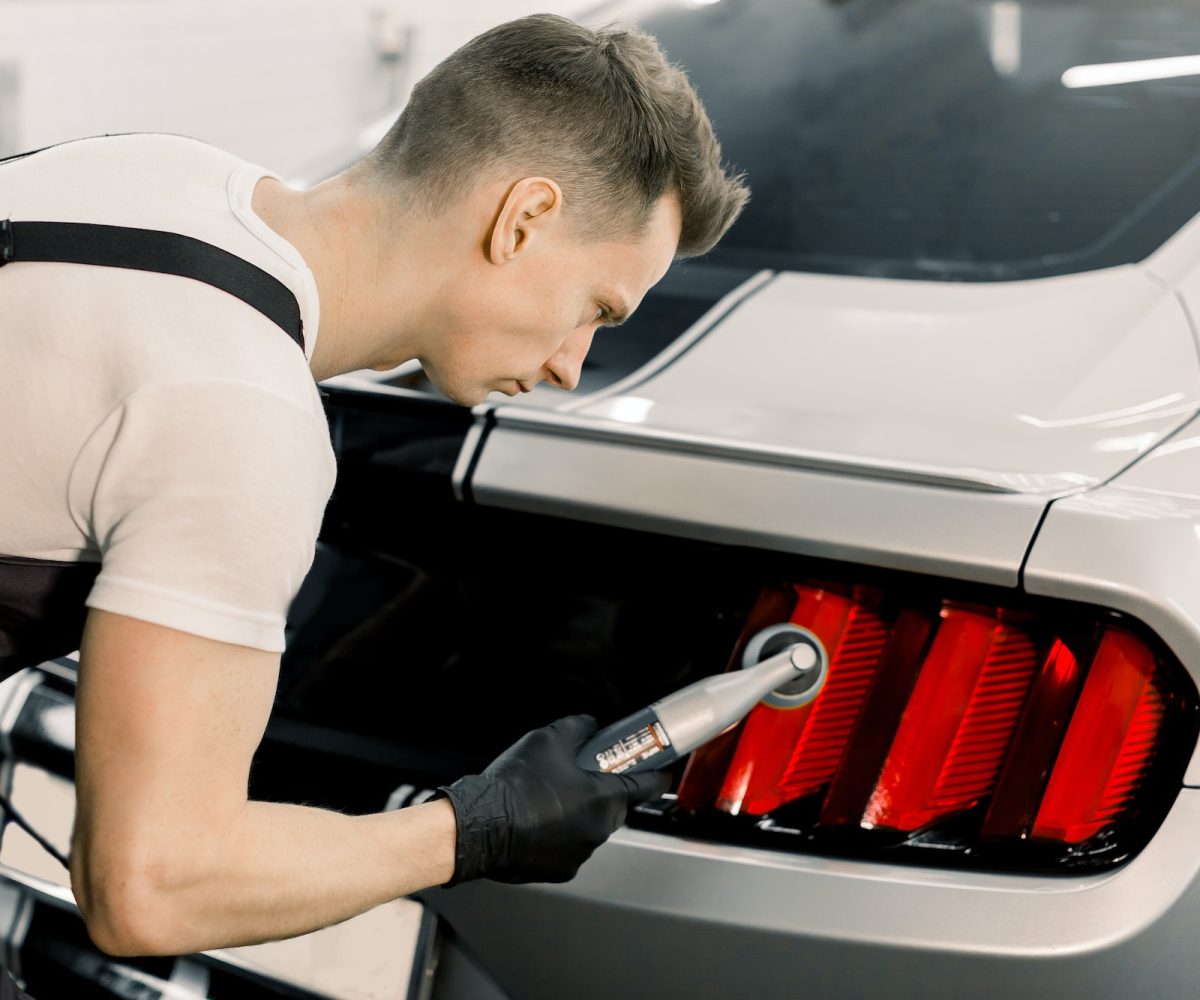 Detailing and polishing of car tail light on car. Young professional concentrated Caucasian male